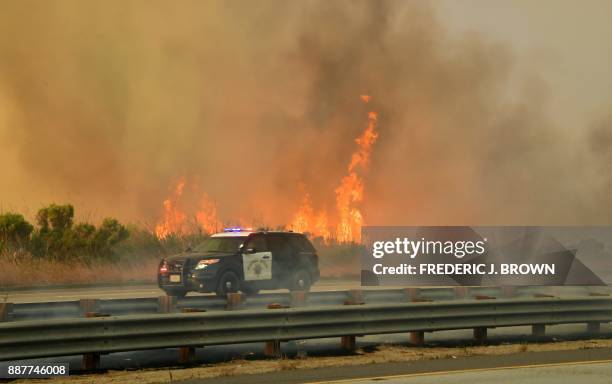 California Highway Patrol vehicle passes a fire on the southbound side of the US 101 freeway in Mondos Beach, west of Ventura, California on December...