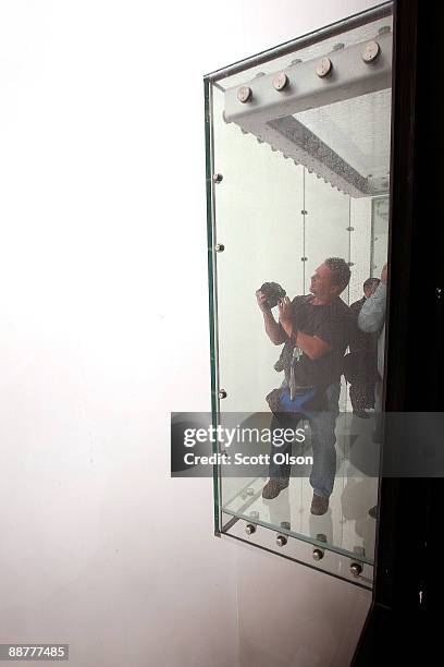 Photographer shoots from the Ledge, a new glass cube that juts out from the 103rd floor Skydeck of the Sears Tower, during a media preview July 1,...