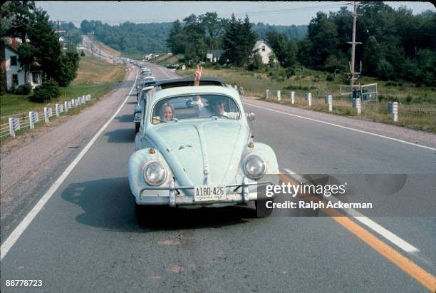 Man driving a Volkswagen Beatle on the way to the Woodstock Music Fetival flashes a peace sign through the sun roof of the car, Bethel, NY, August...