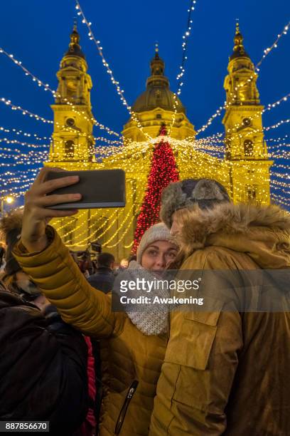 Couple take a selfie in front of Saint Stephen on December 7, 2017 in Budapest, Hungary. The traditional Christmas market and lights will stay until...