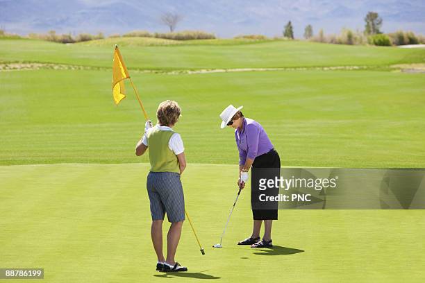 senior woman putts on green - golf putter stock pictures, royalty-free photos & images