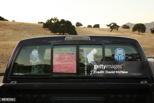 Images of remembrance are displayed on the window of a pickup truck parked along the road outside of Neverland Ranch as preparations are made for...