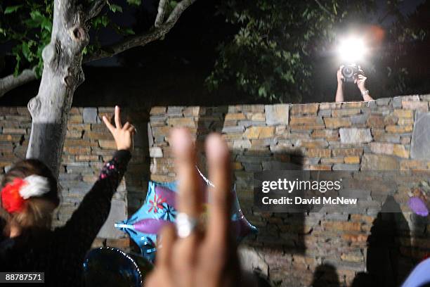 Fans outside the gates of Neverland Ranch gesture toward an unseen photographer taking a picture from inside Neverland Ranch wall as preparations are...