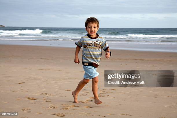 young boy running along a beach. - coffs harbour stockfoto's en -beelden