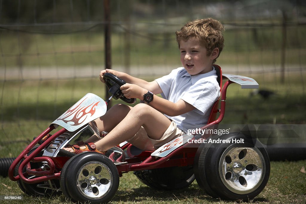 Young boy child driving red Go Kart car 