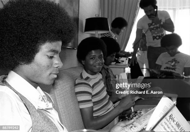 The Jacksons in a hotel room, with Michael Jackson reading a newspaper and Randy Jackson looking to camera, in New York in 1977.