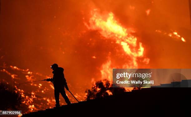 Resident waters a roof as the Thomas Fire approaches the town of La Conchita early Thursday morning.