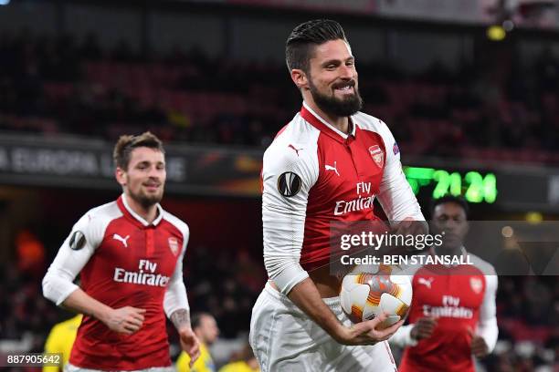 Arsenal's French striker Olivier Giroud pops a ball up his shirt as he celebrates scoring a penalty, the fifth goal, during the Europa League Group H...