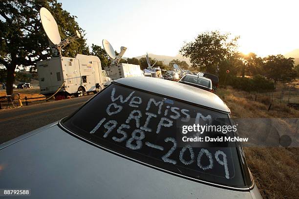 The sun rises behind messages of remembrance on a fan's car parked near television news satellite trucks on the country road outside the gates of...