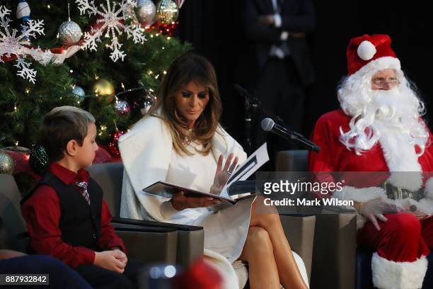First lady Melania Trump sits between Damian Contreras and a person dressed as Santa Claus as she reads the Christmas book, The Polar Express at...
