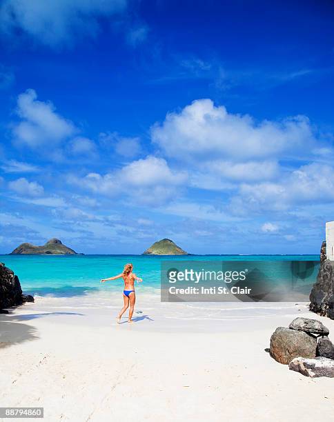 woman walking toward water on lanikai beach - kailua stockfoto's en -beelden