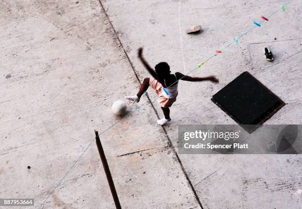 Child, displaced from the island of Barbuda, plays soccer while at a shelter at a cricket stadium on December 7, 2017 in St John's, Antiqua. Barbuda,...