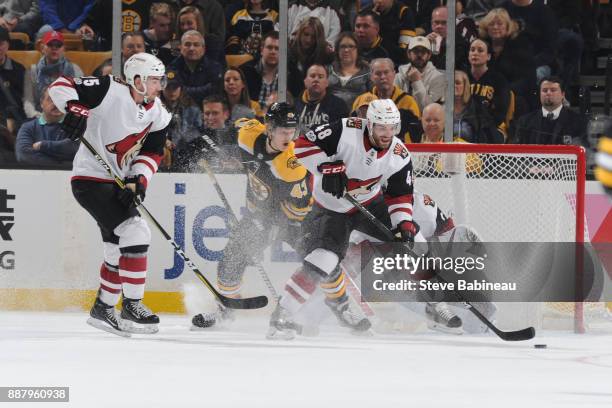 Jordan Martinook and Kyle Capobianco of the Arizona Coyotes against Danton Heinen of the Boston Bruins at the TD Garden on December 7, 2017 in...