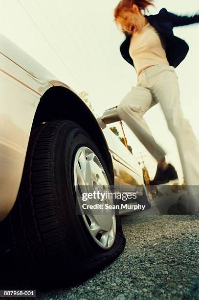 woman kicking flat tyre with frustrated expression, low angle - kicking tire stock pictures, royalty-free photos & images