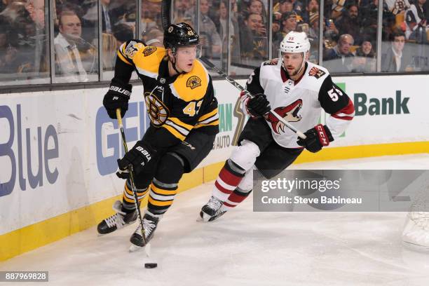 Danton Heinen of the Boston Bruins skates with the puck against Jason Demers of the Arizona Coyotes at the TD Garden on December 7, 2017 in Boston,...