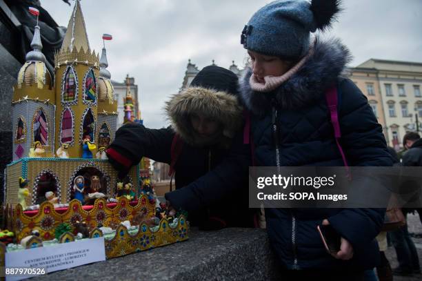 Two kids seen interacting with a nativity scene during the 75th edition of Christmas Cribs competition. The 'cribs' are nativity scenes, but...