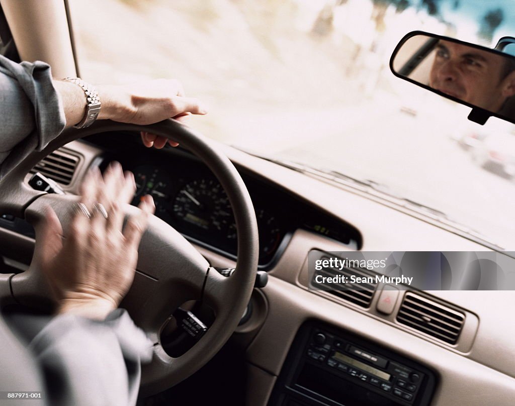 Man honking horn on motorway with frustrated expression (blurred motio