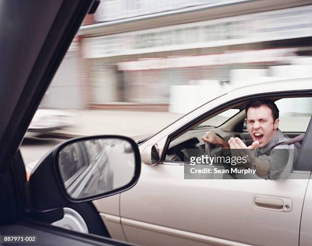 man in car gesticulating angrily at another driver (blurred motion) - rabbia emozione negativa foto e immagini stock