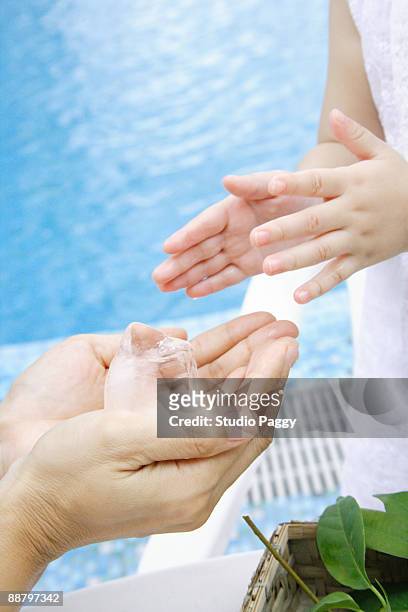 close-up of a woman's hands holding an ice cube in front of her daughter - ice cube family 個照片及圖片檔