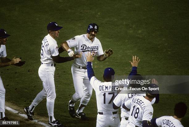 Outfielder Kirk Gibson of the Los Angeles Dodgers rounds third base and is greeted by teammates after he hit a pitch hit homerun in the bottom of the...