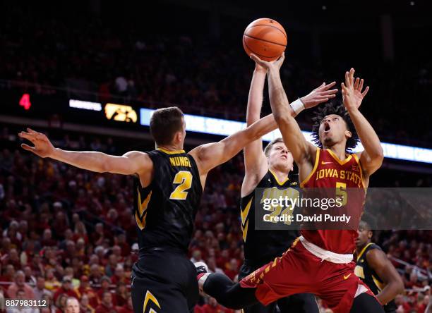 Lindell Wigginton of the Iowa State Cyclones takes a shot as Jack Nunge of the Iowa Hawkeyes, and Brady Ellingson of the Iowa Hawkeyes block in the...