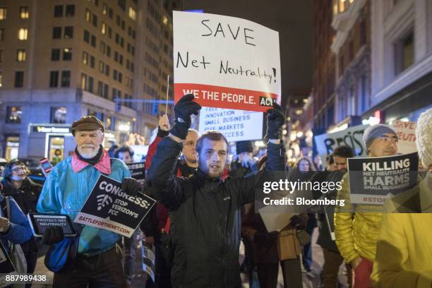 Demonstrators hold up signs during a net neutrality protest outside a Verizon Communications Inc. Store in Boston, Massachusetts, U.S., on Thursday,...