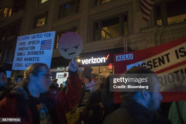 Demonstrators hold up signs during a net neutrality protest outside a Verizon Communications Inc. Store in Boston, Massachusetts, U.S., on Thursday,...