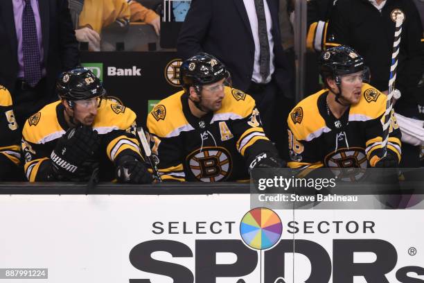 Brad Marchand, Patrice Bergeron and David Pastrnak of the Boston Bruins watch the play from the bench against the Arizona Coyotes at the TD Garden on...