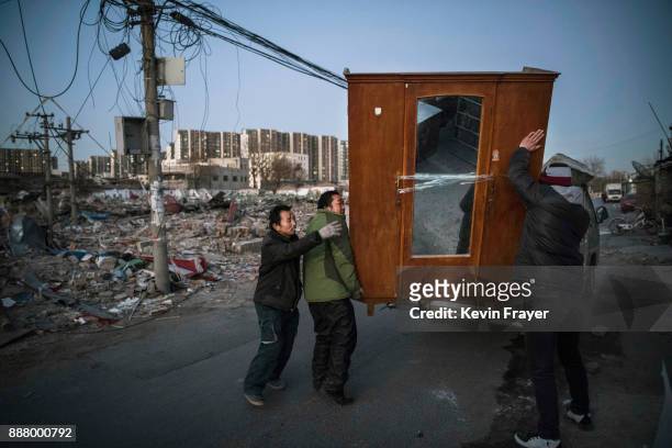 Chinese migrant workers from Anhui load furniture on a truck after being evicted from their home next to the rubble of buildings demolished by...