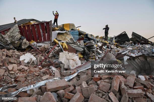 Chinese workers salvage items from buildings demolished by authorities in an area that used to have migrant housing and factories on December 6, 2017...