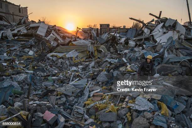 Chinese worker salvages items from buildings demolished by authorities in an area that used to have migrant housing and factories on December 6, 2017...