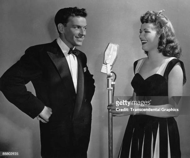 Frank Sinatra speaks with Barbara Hale at the microphone during a radio broadcast around 1940 in New York.
