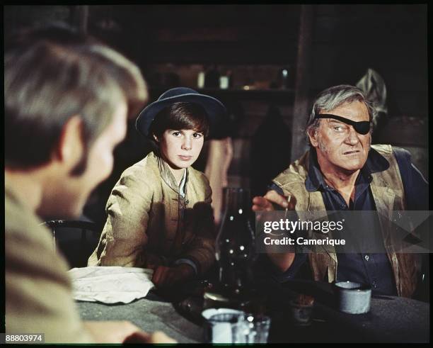 John Wayne points ominously at Glen Campbell, while sitting next to the actress Kim Darby in this scene from the western "True Grit", 1969.