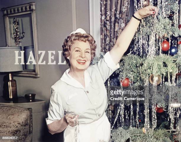 Shirley Booth smiles while trimming a Christmas tree in this scene from the television series "Hazel", ca.1960s.