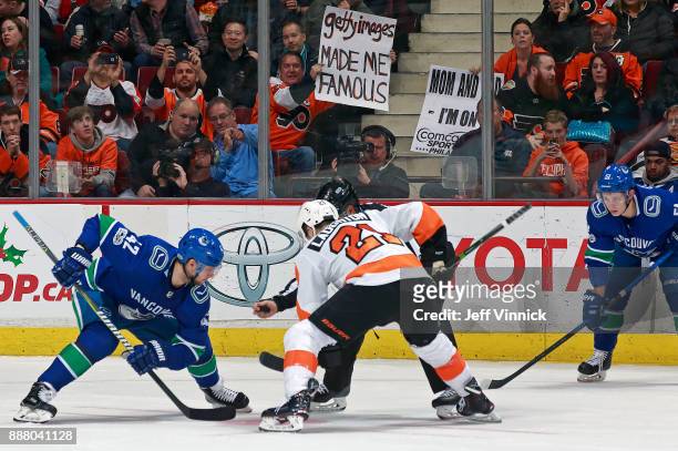 Fan holds up a sign as Alexander Burmistrov of the Vancouver Canucks faces off against Scott Laughton of the Philadelphia Flyers during their NHL...
