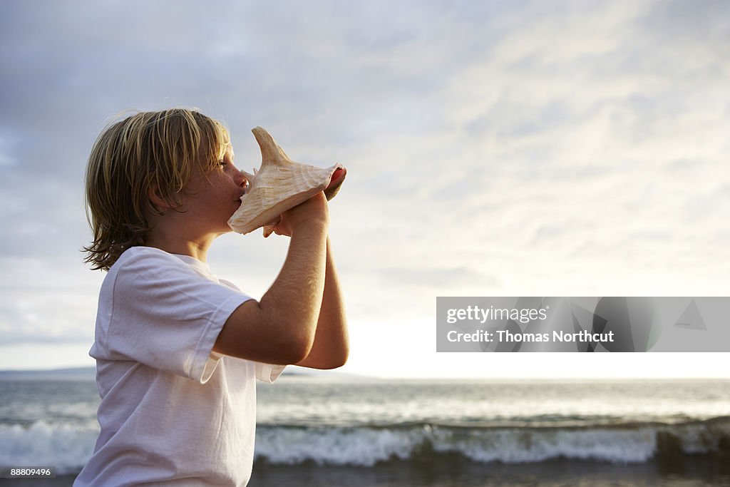 Boy blowing into conch shell