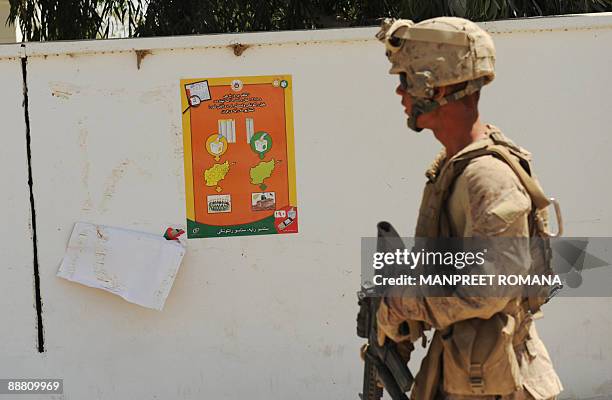 Marine of 2nd Marine Expeditionary Brigade walks past an educational poster about upcoming Afghan elections as he patrols Garmsir district in...