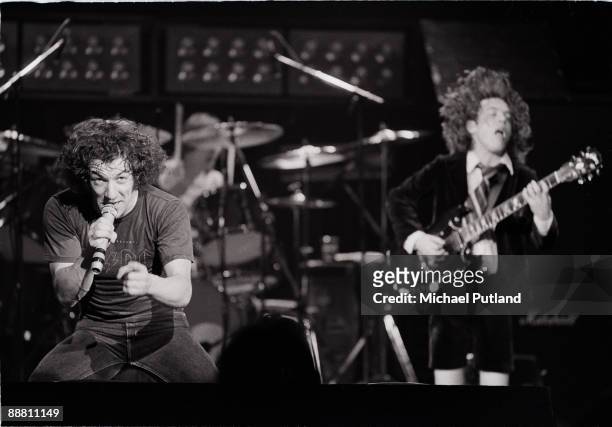 Singer Brian Johnson and guitarist Angus Young performing with heavy rock group AC/DC on tour in the UK, 1981. In the background is drummer Phil...