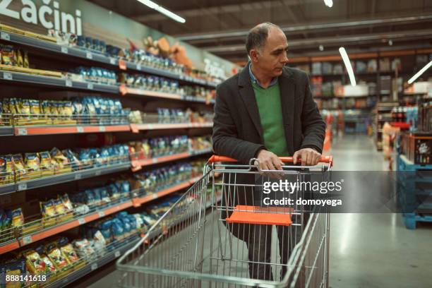 bel homme mature, faire du shopping dans le supermarché - produce aisle photos et images de collection