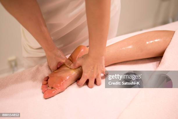 woman receiving foot massage with oil - woman lying on stomach with feet up stock pictures, royalty-free photos & images