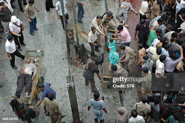 Indian security personnel and bystanders help carry victims of a bus accident onto pushcarts at a railway station in Howrah, near Kolkata, on July 4,...
