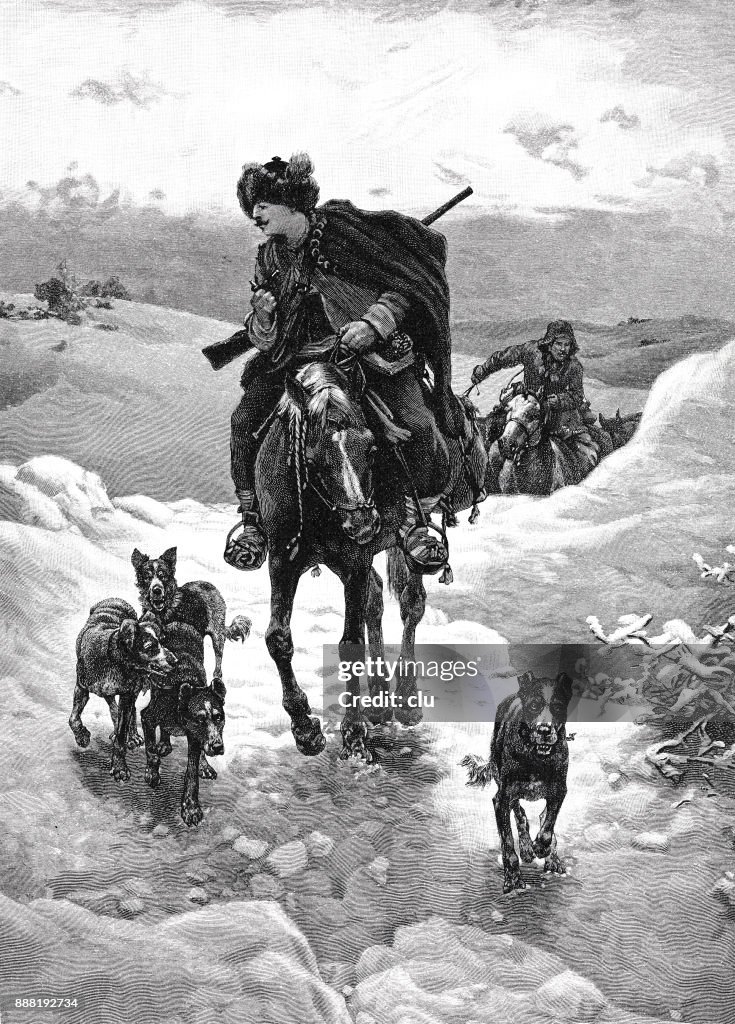 Hunter riding on horse and dogs running aside