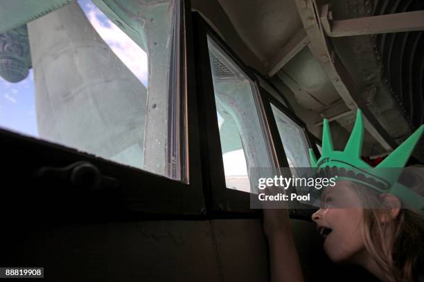 Aleyna Bartnick of Merrick, New York looks up toward the torch as she takes in the view from the crown of the Statue of Liberty on July 4, 2009 in...