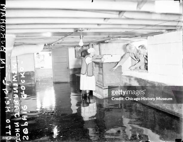 Informal portrait of Sophie Etocko standing ankle-deep in water in a flooded house in Burnham, Illinois, after the flooding of the Calumet River,...