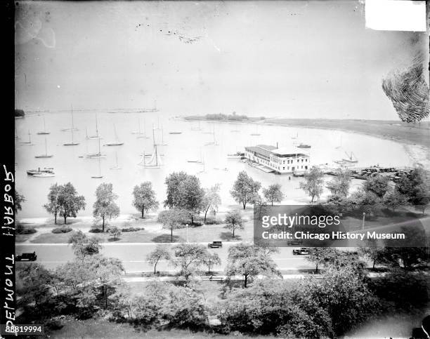 View of sailboats sitting in water in Belmont Harbor, located in the Lake View community area of Chicago, Illinois, 1929. Automobiles are driving...