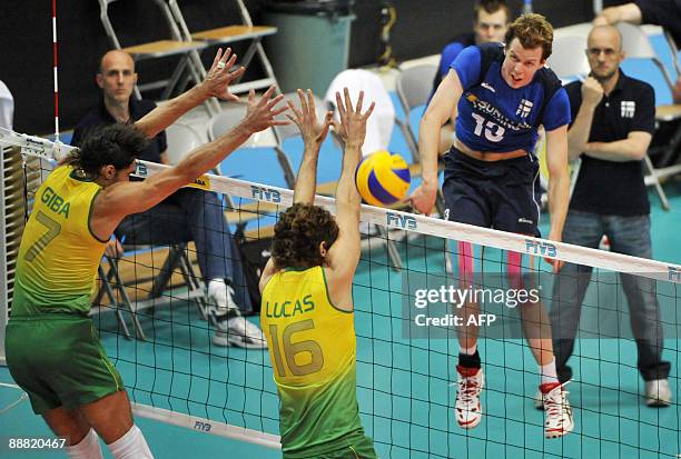 Brazil's Giba and Lucas Saatkamp jump to block a spike by Finland's Mikko Oivanen while Finland's head coach Mauro Berruto looks on in the background...