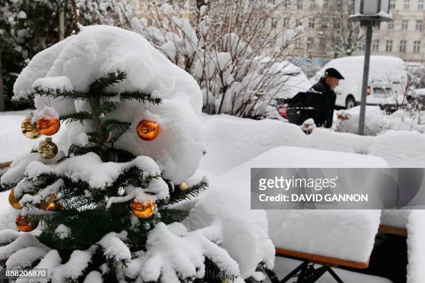 Man walks past a restaurant where a Christmas tree, tables and benches are covered with snow in Berlin's Kreuzberg district January 2, 2010. Winter...