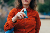 Young woman using an asthma inhaler outdoors