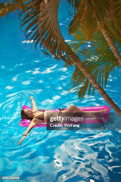 young woman vacationing relaxing in tropical swimming pool - swimming float stock pictures, royalty-free photos & images