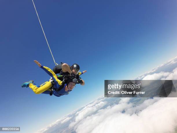 a tandem skydiving passenger has much fun flying in the blue sky over a white cloud. - northern european descent ストックフォトと画像